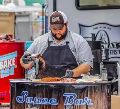 Joe Pearce of Slap's BBQ seasoning meat at a barbecue competition
